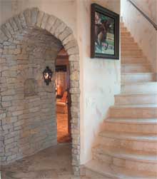 An arched-stone hallway leads down to the game room while marble steps lead up to the yoga room.