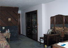 Before: Wood-covered walls and blue carpet lend an outdated feel to this bedroom. 